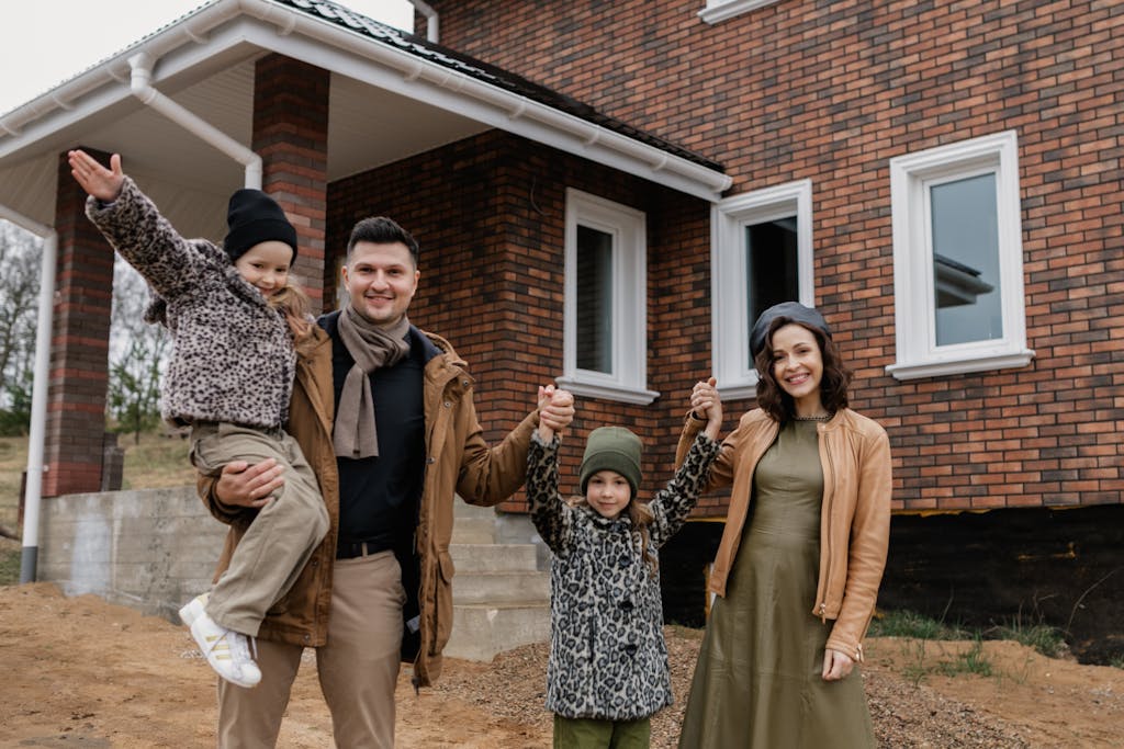 Joyful family celebrates new home purchase with smiles and warm attire.